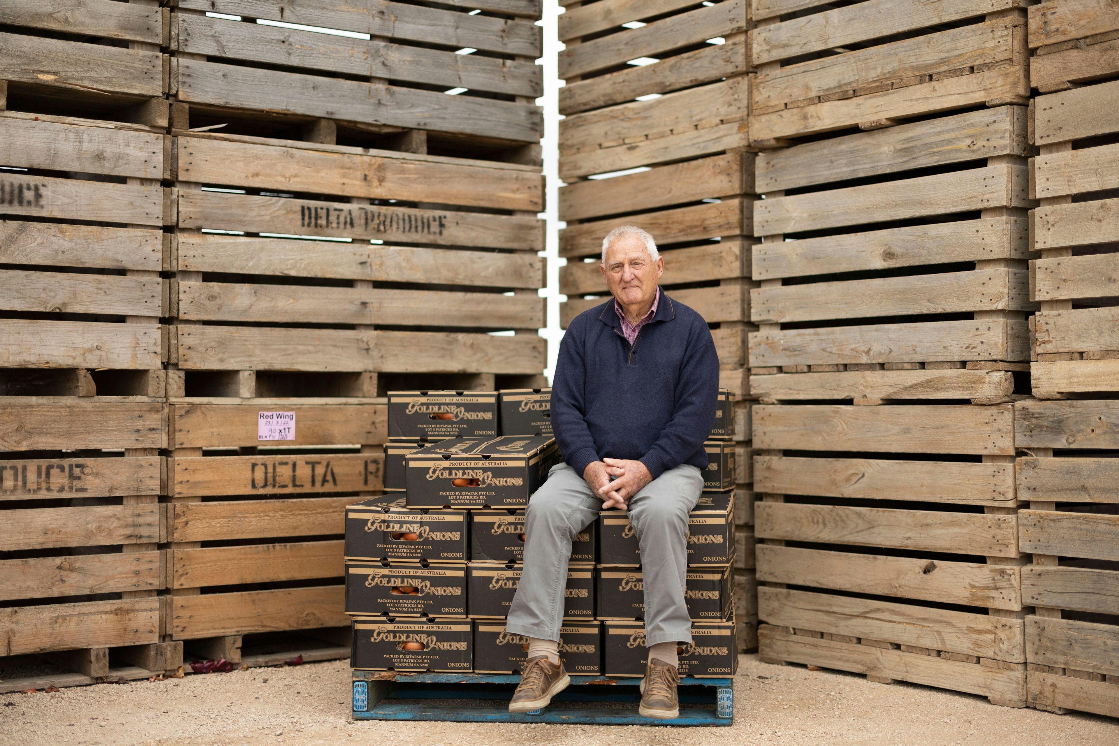 Riverpak onion farmer sitting on onion boxes surrounded by crates